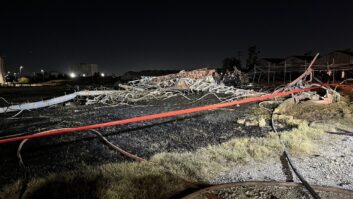 A communications tower lies crumpled on the ground in a nighttime photo.