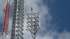 A section of broadcast tower is shown being lifted into place