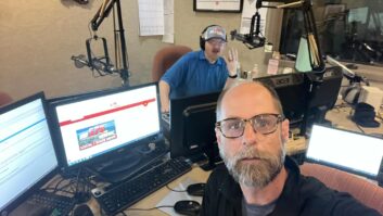 Two men sit in a radio studio, looking at the camera