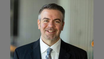 A man in suit and tie smiles at the camera.