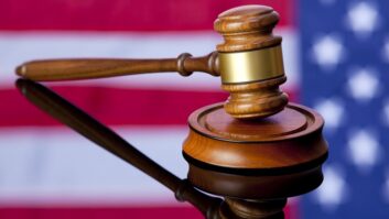 A judicial gavel sitting on a tabletop in which the colors of the US flag are reflected