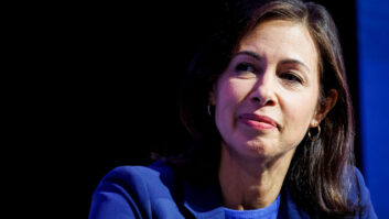 A woman in blue business dress is shown in a head and shoulders photograph