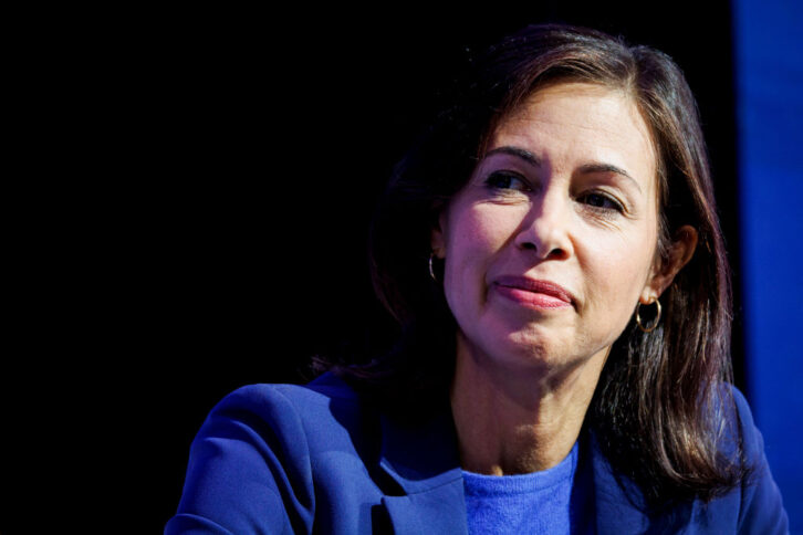 A woman in blue business dress is shown in a head and shoulders photograph