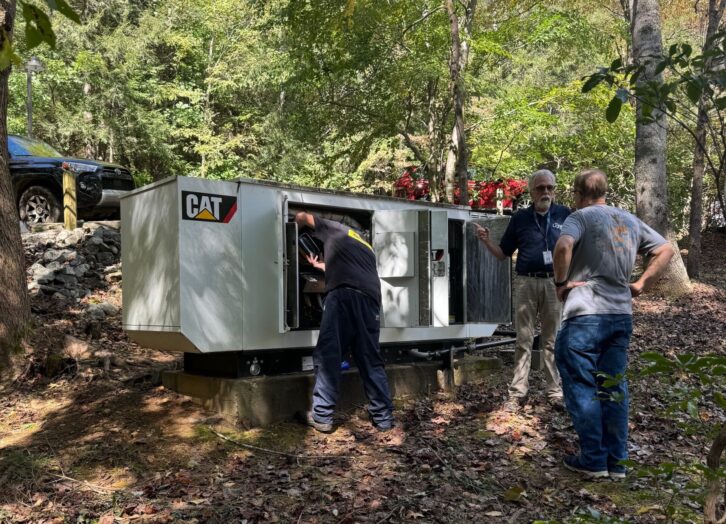 Keith Pittman, WMIT(FM)'s technical and facilities manager, and Steve McPeters, managing director, accounting and administration, observe a technician from Carolina Cat with a Caterpillar generator.