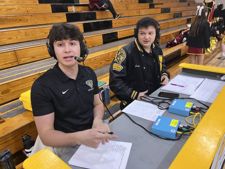 Max Swain and Jake Jira call a game. Sports Pods are on the table in front of them.